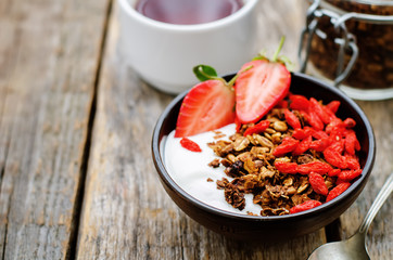 fresh breakfast of granola, yogurt, nuts, goji berries and straw