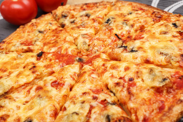 Pizza, geschnitten mit Tomaten im Hintergrund