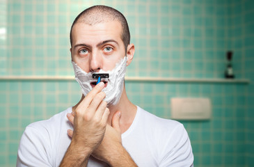 Man using a disposable razor to shave his beard off