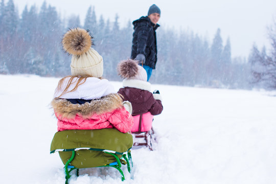 Happy Family Sledding In Winter Outdoors