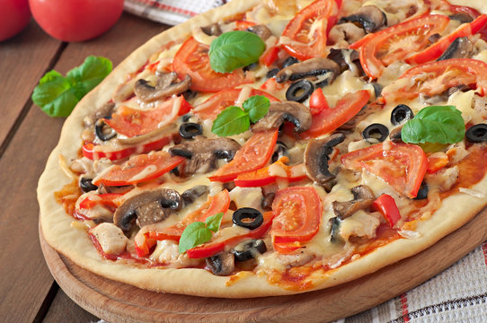 Appetizing pizza with chicken, tomatoes, peppers and mushrooms