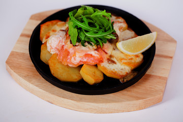 Salmon baked with potatoes and lemon on a cast iron skillet