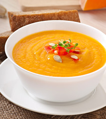 Delicious cream of pumpkin soup in a bowl on wooden table