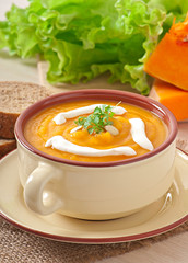 Delicious cream of pumpkin soup in a bowl on wooden table