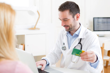 Fototapeta premium Young attractive doctor taking health insurance card