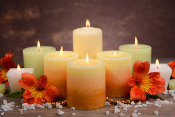 Beautiful candles with flowers on table on brown background