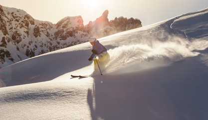 Male skier on downhill freeride with sun and mountain view
