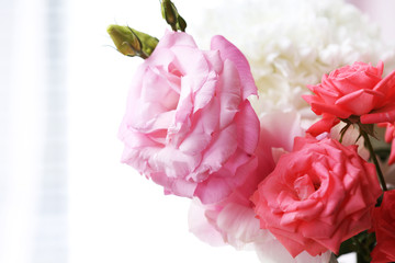 Beautiful flowers in vase with light from window, close-up