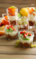 Healthy layered desserts with muesli and fruits on table
