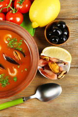 Tasty soup with shrimps, mussels, tomatoes and black olives in