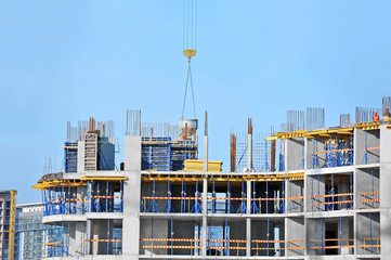 Crane lifting concrete mixer container against blue sky