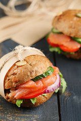 Sandwiches with salmon and vegetables on wooden background