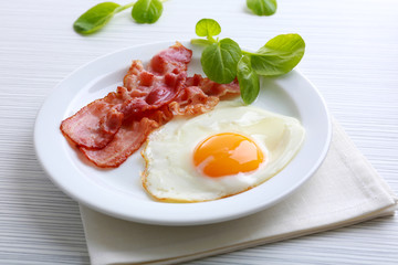 Bacon and eggs on color wooden table background
