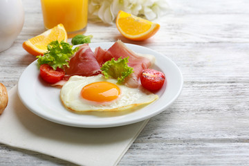 Fototapeta premium Bacon and eggs on color wooden table background.