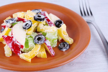 Waldorf salad with olive on plate on wooden background