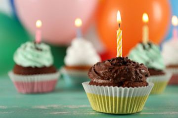 Delicious birthday cupcakes on table on bright background