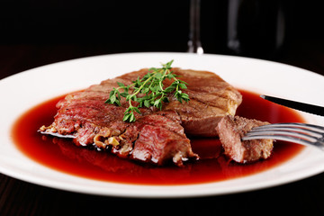 Grilled steak in wine sauce on plate on table close up