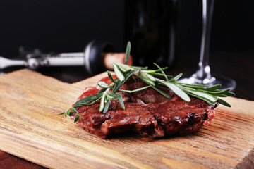 Grilled steak with bottle of wine on dark background