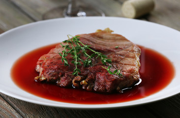 Grilled steak in wine sauce on plate on table close up