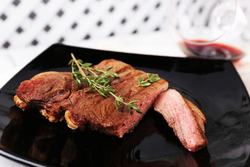 Steak with herbs on plate with wine on wooden background