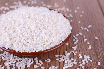 Fototapeta na wymiar Grain of rice on plate on wooden background