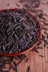 Black rice on plate on wooden background