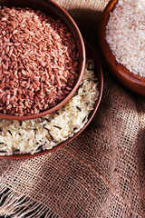 Different kinds of rice in bowls on sackcloth background