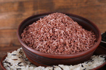 Different kinds of rice in bowls on wooden background