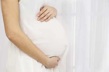 Young pregnant woman on light background