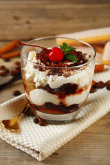 Tasty tiramisu dessert in glass, on napkin, on wooden