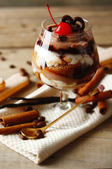 Tasty tiramisu dessert in glass, on wooden background