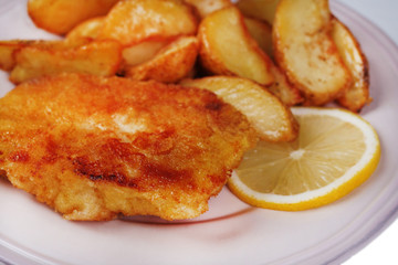 Breaded fried fish fillet and potatoes with sliced lemon