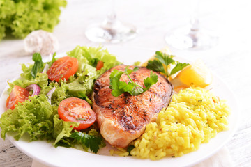 Tasty baked fish with rice on plate on table close-up