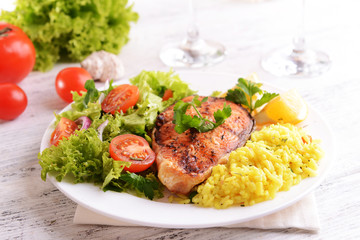 Tasty baked fish with rice on plate on table close-up