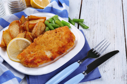 Breaded fried fish fillet and potatoes with asparagus and