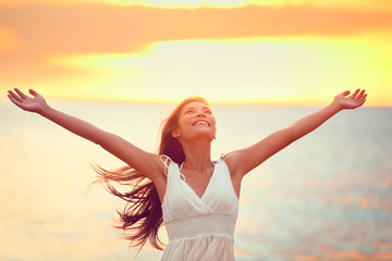 Free happy woman praising freedom at beach sunset