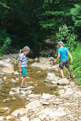 Two kids playing near a mountain stream