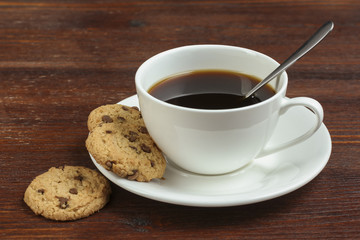 chocolate cookies and cup of hot coffee on old wooden table