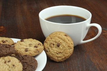 chocolate cookies and cup of hot coffee on old wooden table