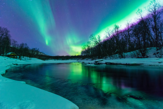 Polarlichter mit Spiegelung über einem vereisten Fluss