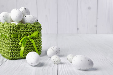 Easter eggs in a green basket on a white table