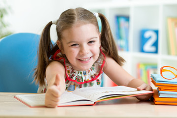 child girl reading story from big book in nursery