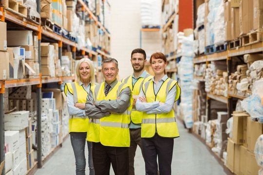 Smiling warehouse team with arms crossed