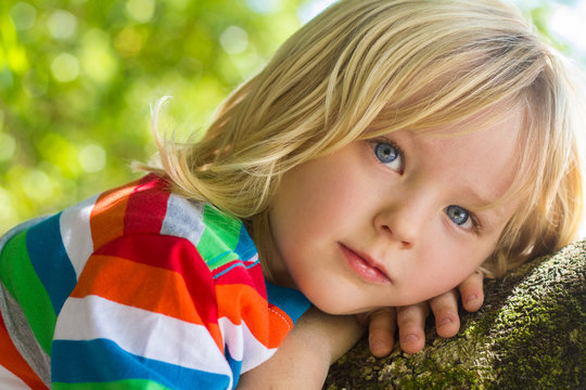 Cute child relaxing deep in thought in a tree