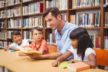 Cute pupils and teacher reading in library