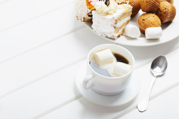coffee with marshmallow and cake on white wooden background