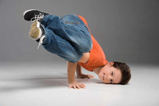 little break dancer showing his skills on grey background.