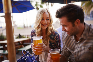 Naklejka premium romantic couple drinking beer at outdoor restaurant