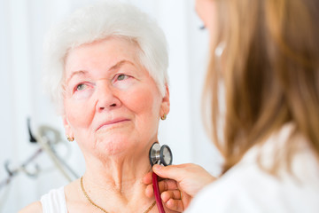 Doktor bei Atmung abhören von Seniorin in Arztpraxis