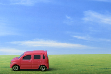 Fototapeta na wymiar 青空と草原と赤いワゴン車